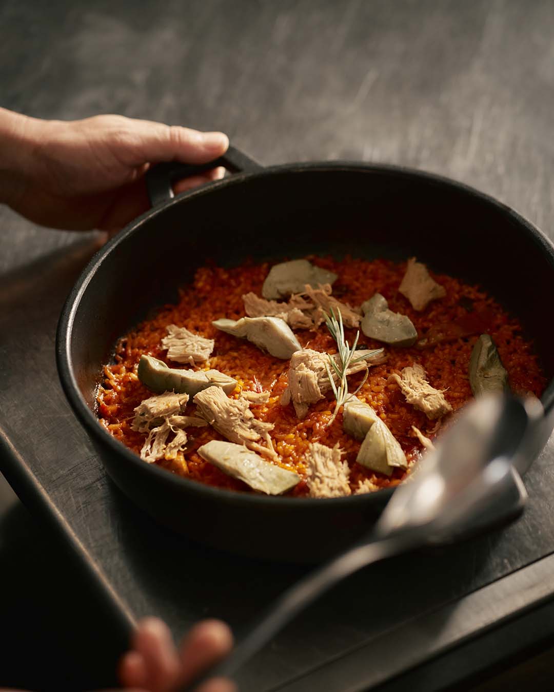 A chef cooking a rice dish with Novameat pulled chicken style and artichokes in professional kitchen for food service